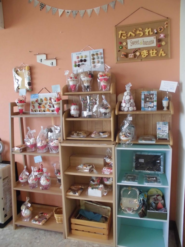 店内のフェイクスイーツ展示コーナー。パフェやケーキの作品が棚いっぱいに並ぶ